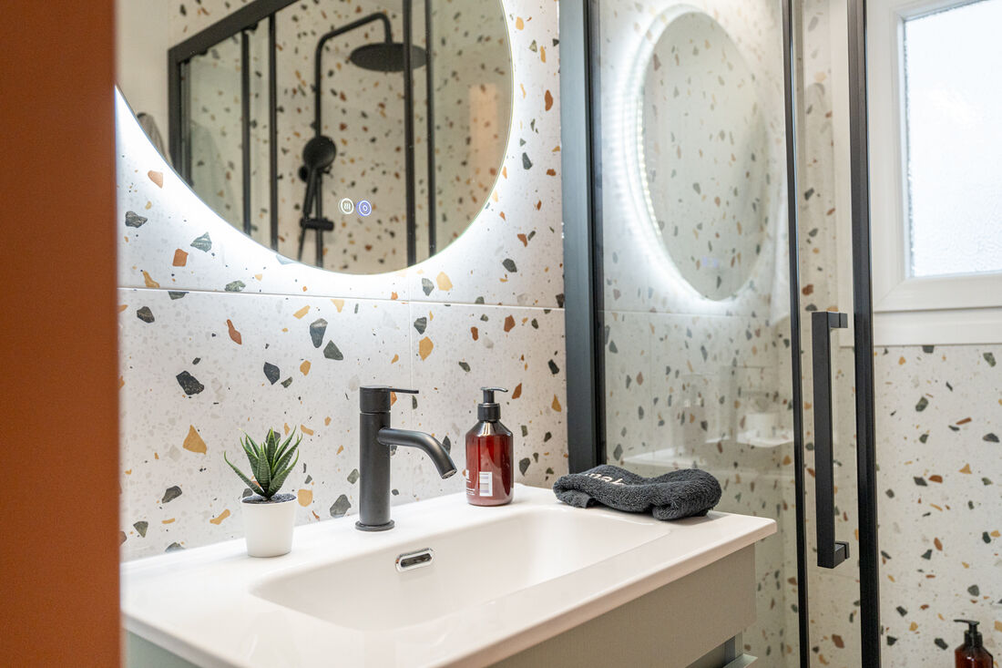 Bathroom sink with backlit mirror and terrazzo tile
