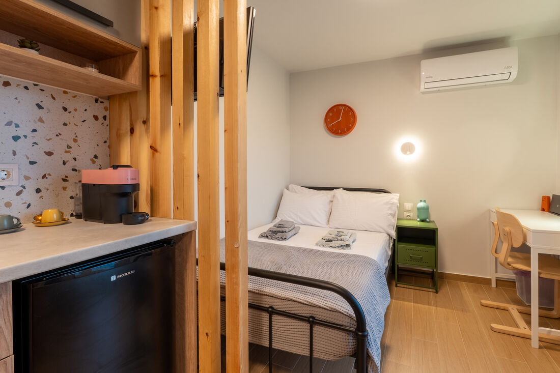 Open-plan studio layout — kitchenette, bed, and desk